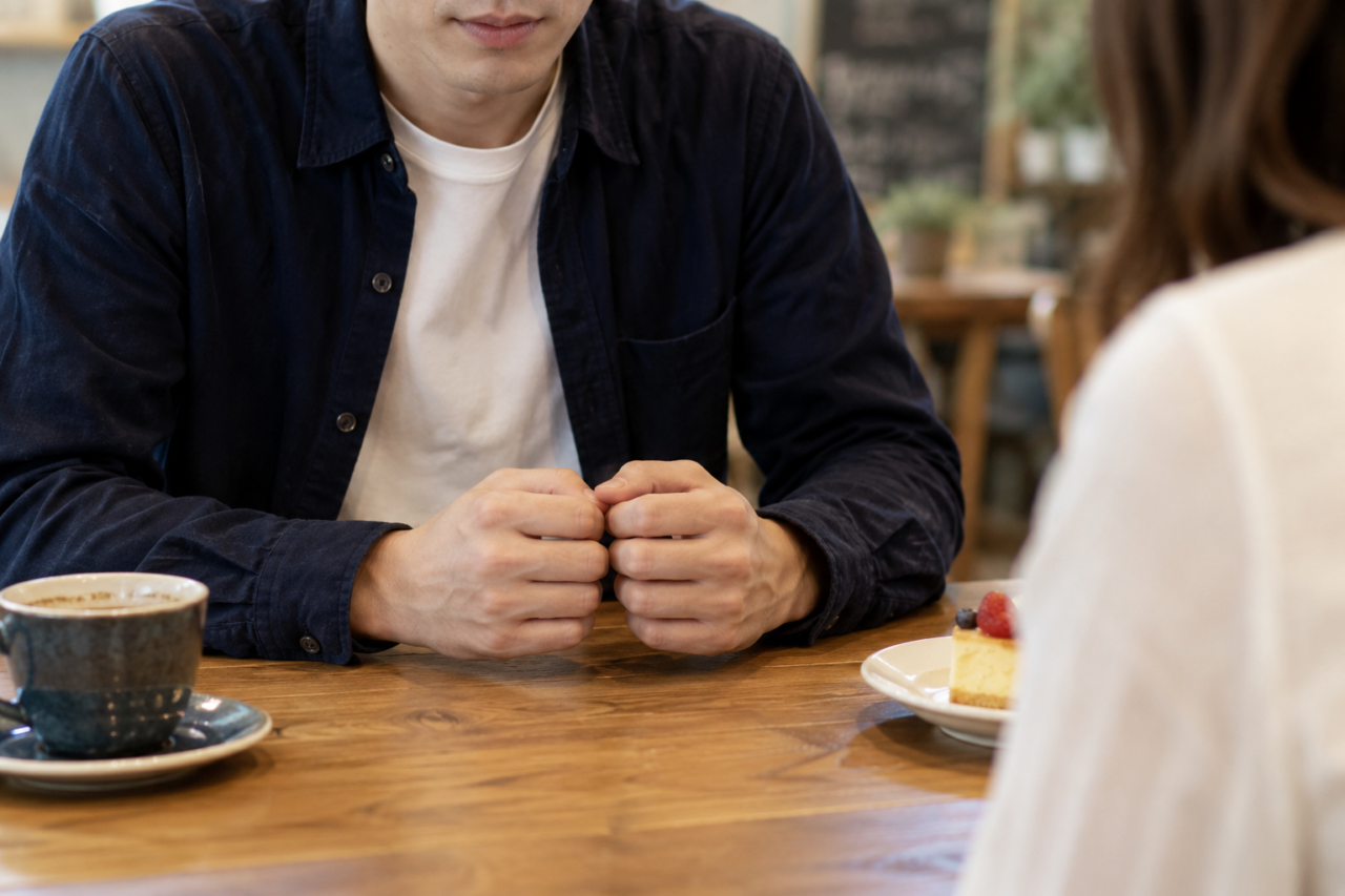 カフェで女性を前に緊張する男性の手元